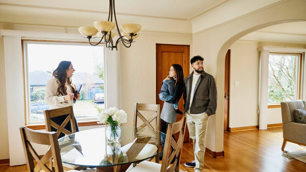 Wide shot of family with toddler walking though dining room of home for sale during open house