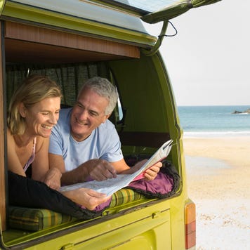 A middle-aged couple looks out to the beach from their van