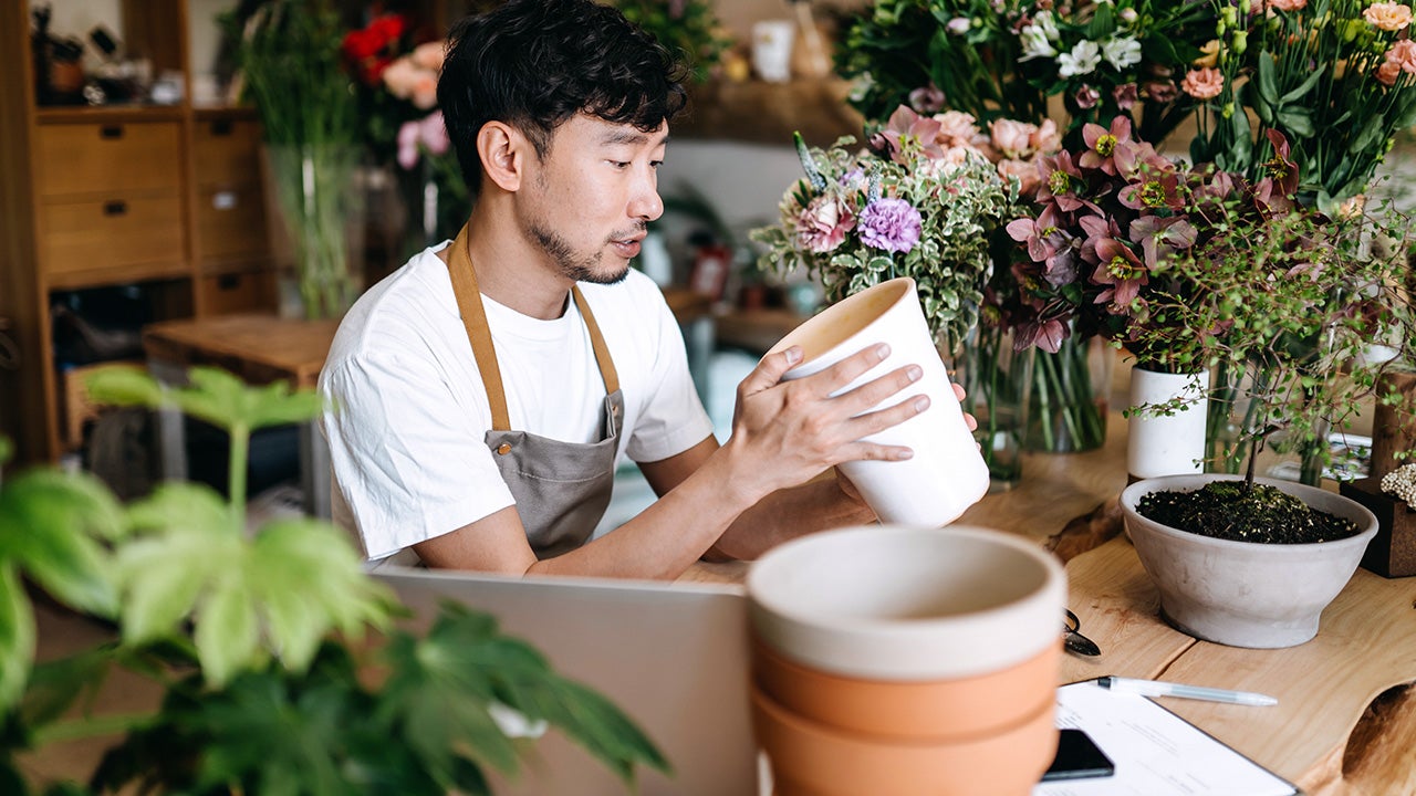 man repotting a plant in a flower shop