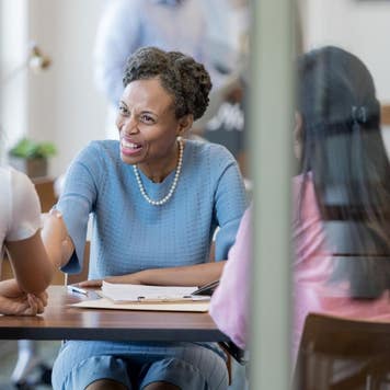 Two women meet with a Black credit union advisor.