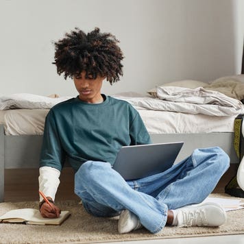 College student studies on floor of bedroom