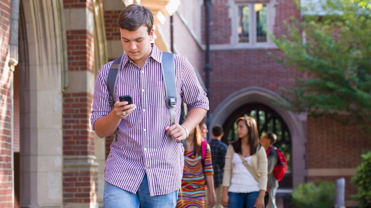 College student walks on campus with a phone