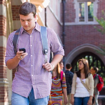 College student walks on campus with a phone