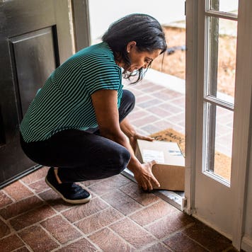 person at door step picking up an amazon box
