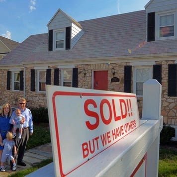 A family stands outside a house they've just purchased