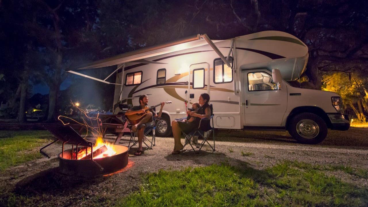 Family enjoying guitar and fire while camping in an RV