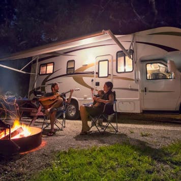 Family enjoying guitar and fire while camping in an RV