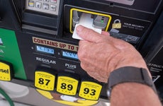 Man inserting credit card into gas pump with high prices