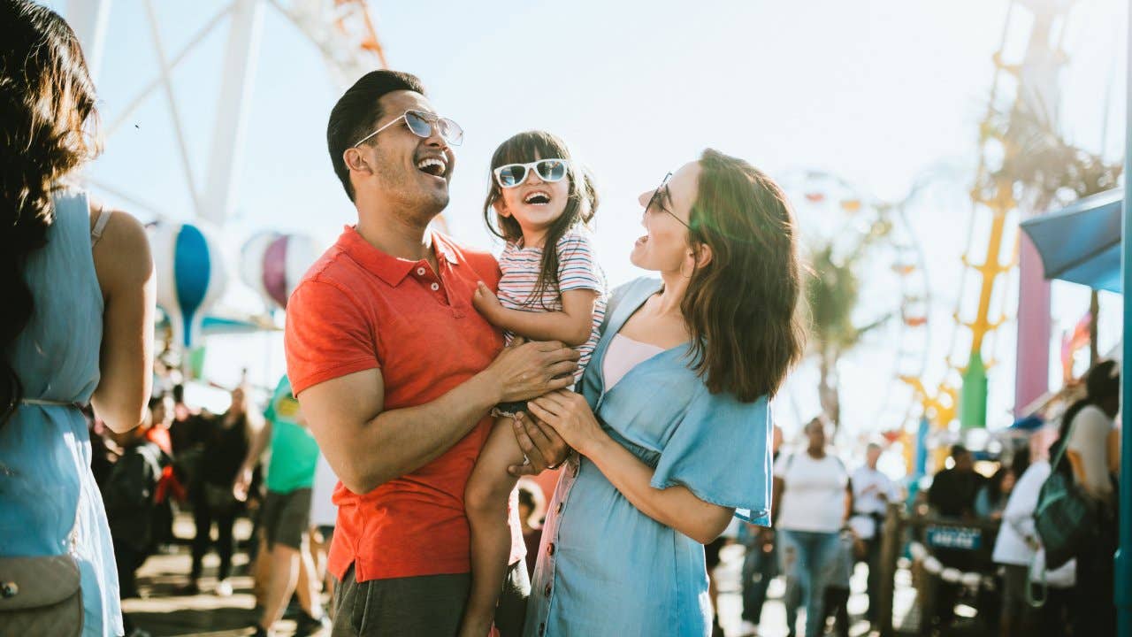 Family having fun at an outdoor carnival. They all wear sunglasses with big smiles.