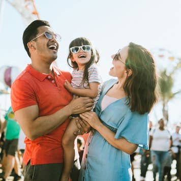 Family having fun at an outdoor carnival. They all wear sunglasses with big smiles.