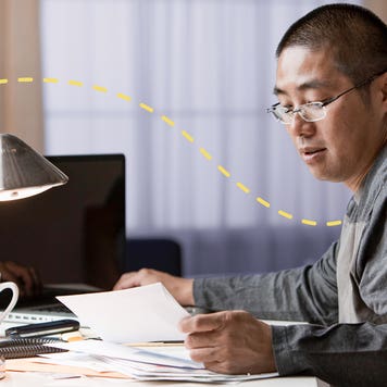man working on computer and looking at papers