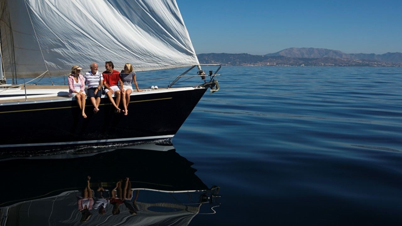 Four people sitting on the side of a sail boat