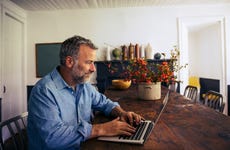 Man sitting at dining room table on laptop