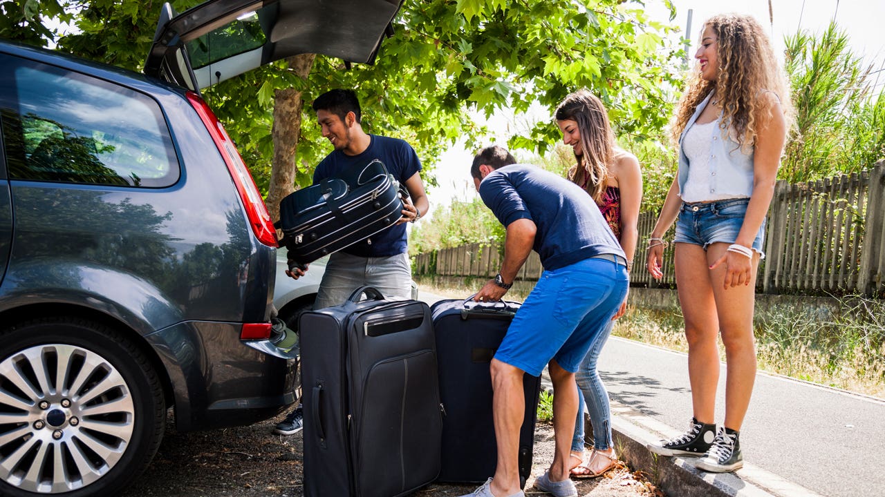 Young group of friends load up their car in preparation for a trip.
