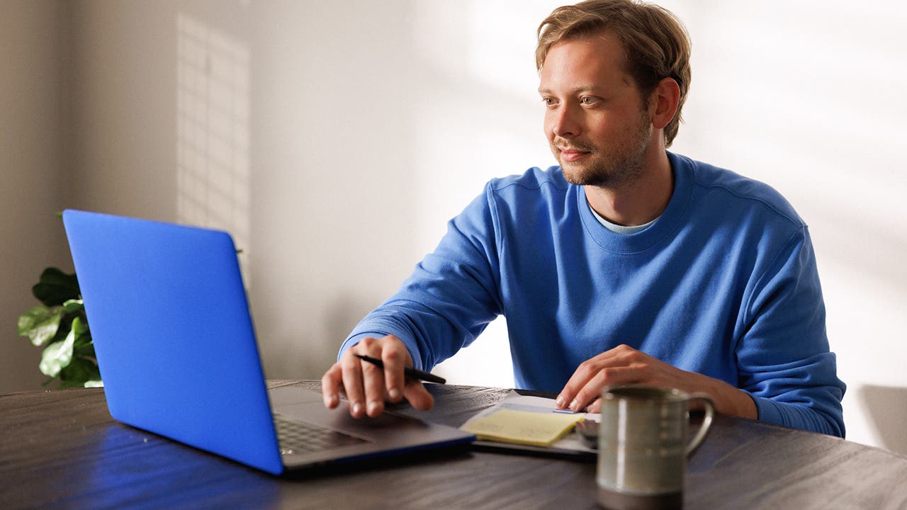 Person in blue sweater using a blue laptop