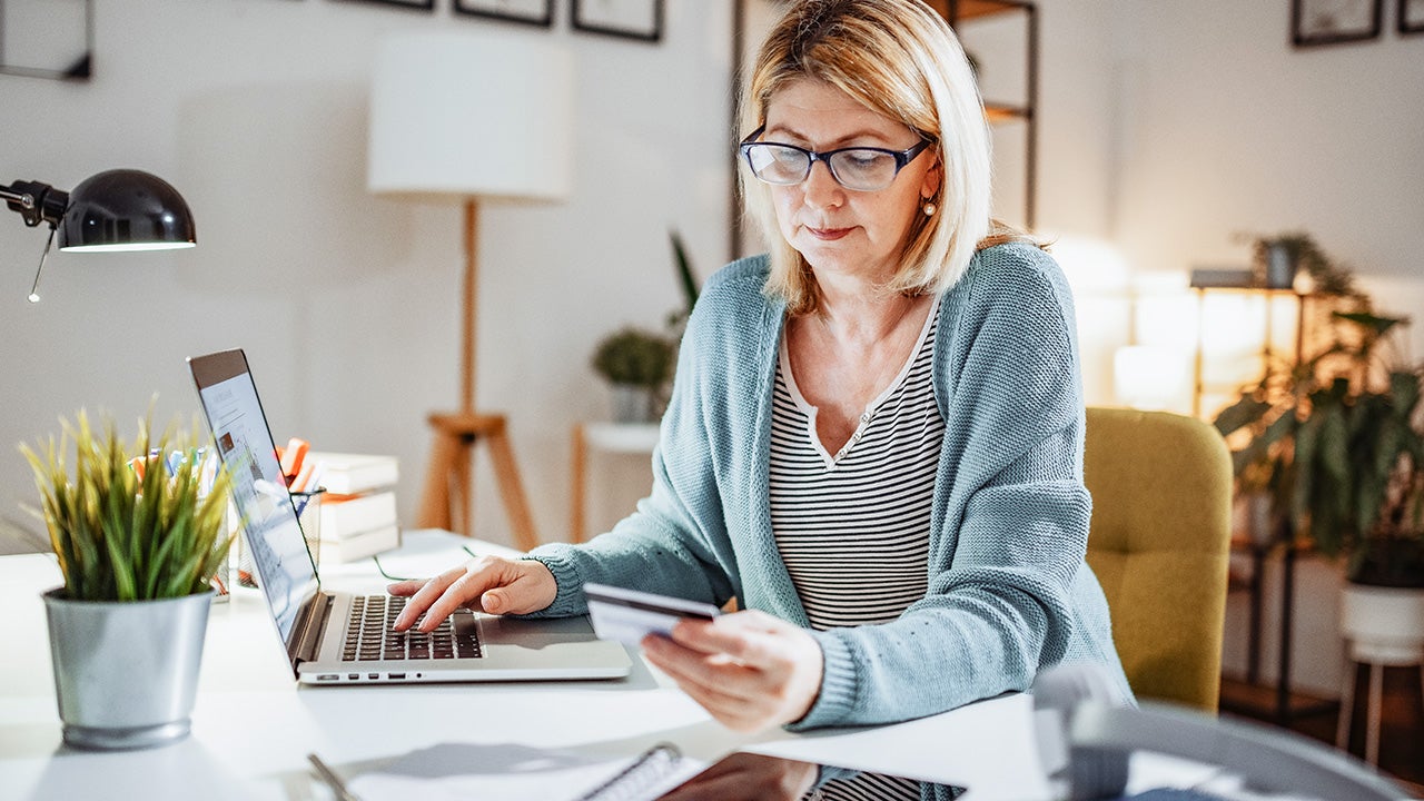 Blonde mature woman at home, working on laptop and dealing with home finances