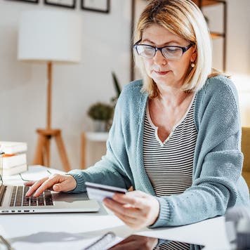 Blonde mature woman at home, working on laptop and dealing with home finances