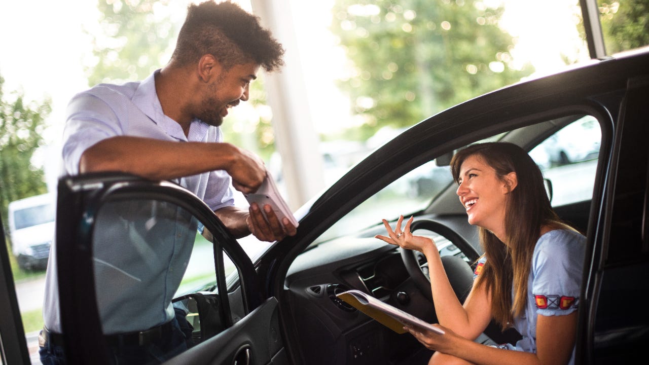 Car salesman talking to woman in car about