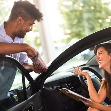 Car salesman talking to woman in car about