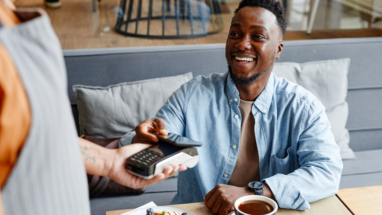 young person paying with card at a table