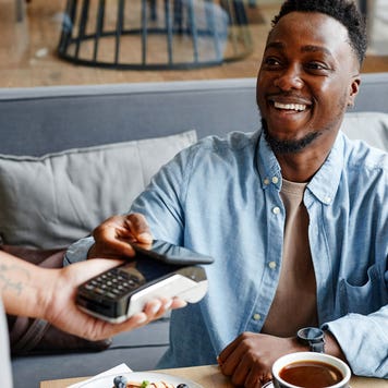 young person paying with card at a table