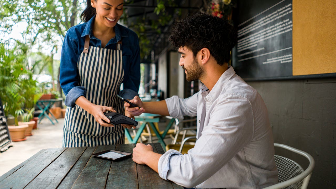 young person paying a dining bill with a card