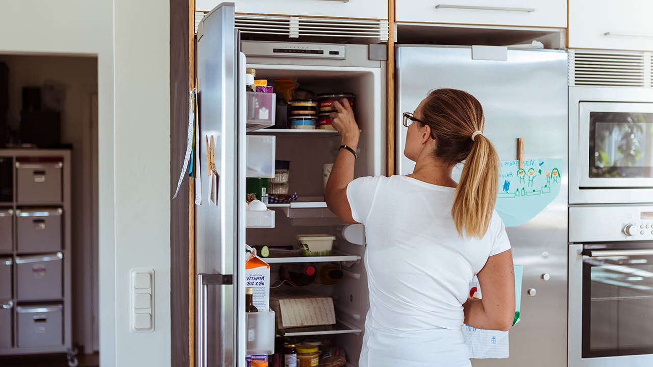 person grabbing food from refrigerator