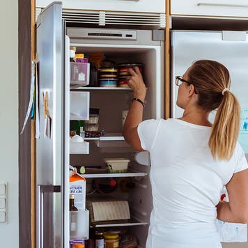 person grabbing food from refrigerator