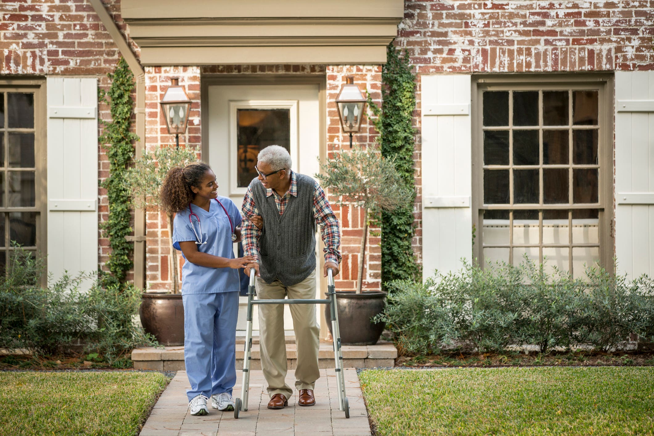African American nurse helping patient use walker