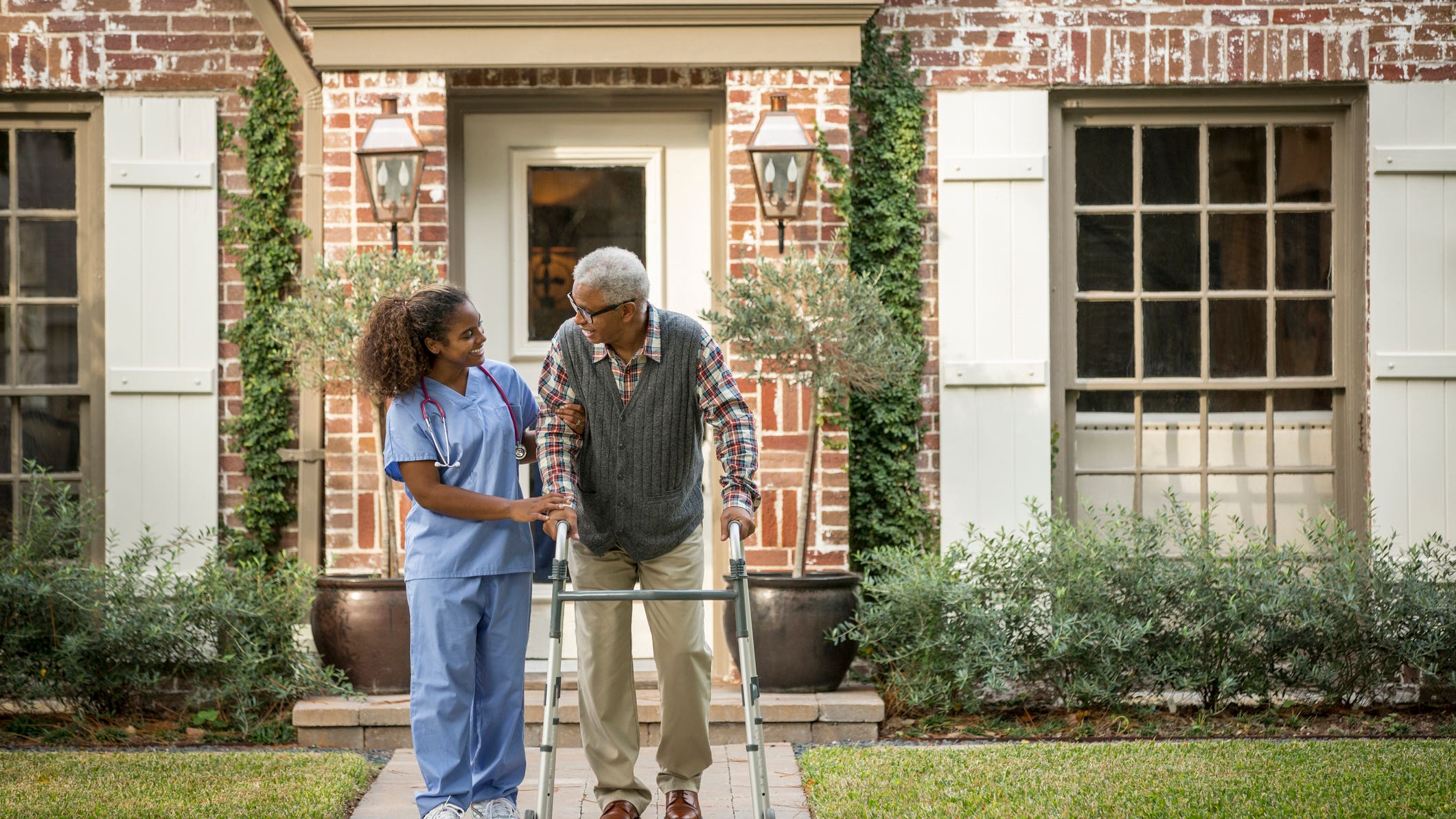 African American nurse helping patient use walker