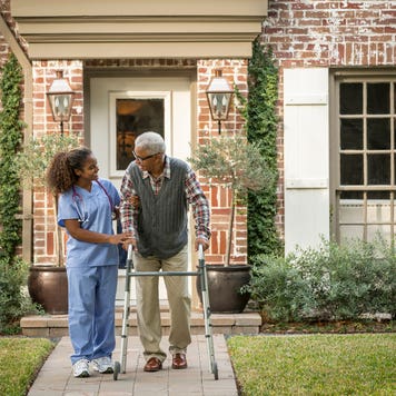 African American nurse helping patient use walker
