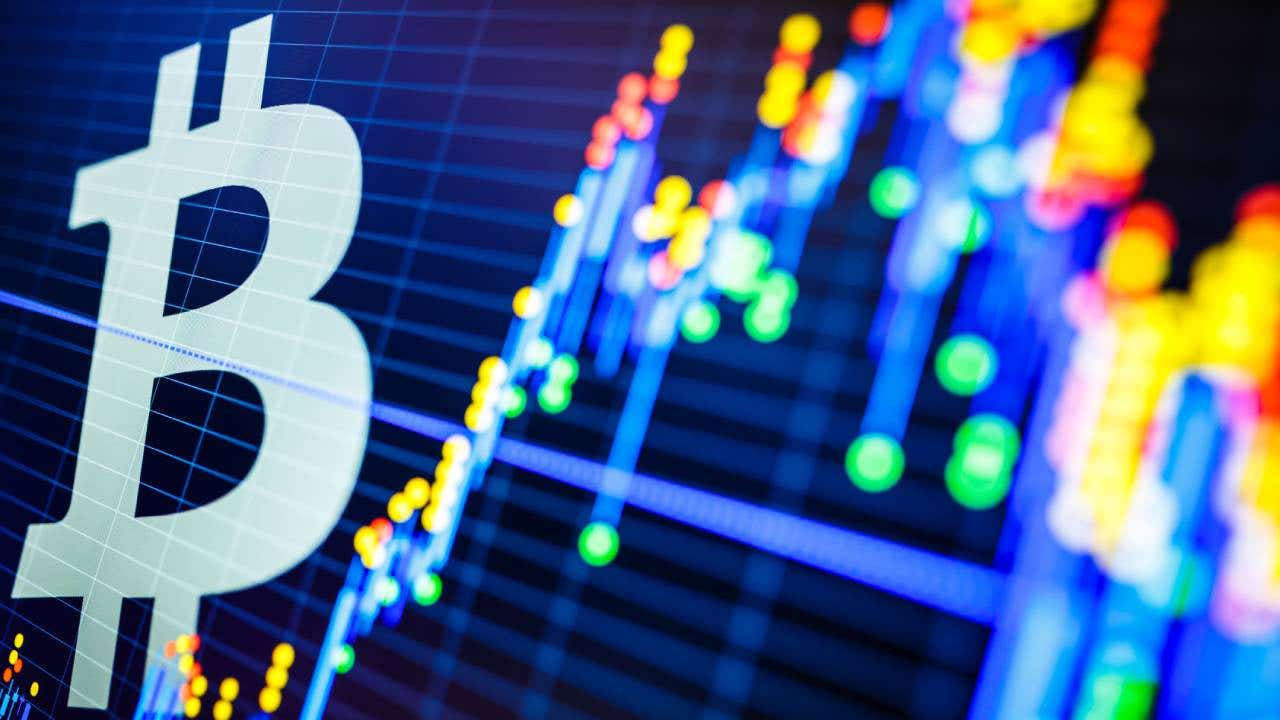 Computer illustration of Bitcoin logo juxtaposed against neon colored financial charts