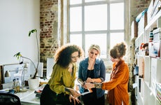 Three women co-workers discuss something in their office