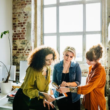 Three women co-workers discuss something in their office