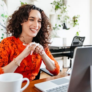 A smiling woman sits at her office desk