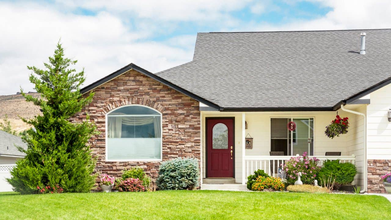 New contemporary home with front lawn, evergreen tree, flowers and shrubs.