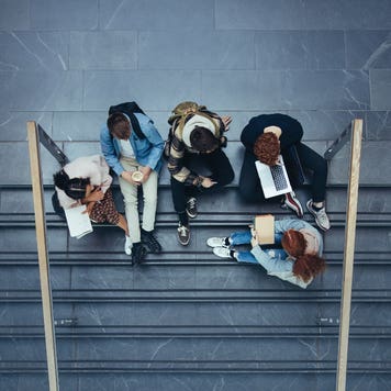Students sit on steps of university building and study