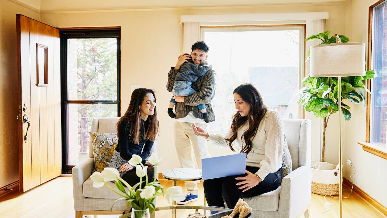 Property owner meeting with prospective tenants - mother, father and toddler - in beige living room with big windows