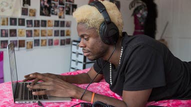 A young man wearing headphones with a laptop