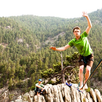 A man walks on a tightrope over a gorge