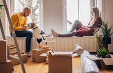 Young couple in an apartment with their dog and some boxes from a recent move.