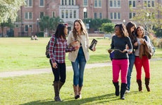 group of college students walking on a campus quad