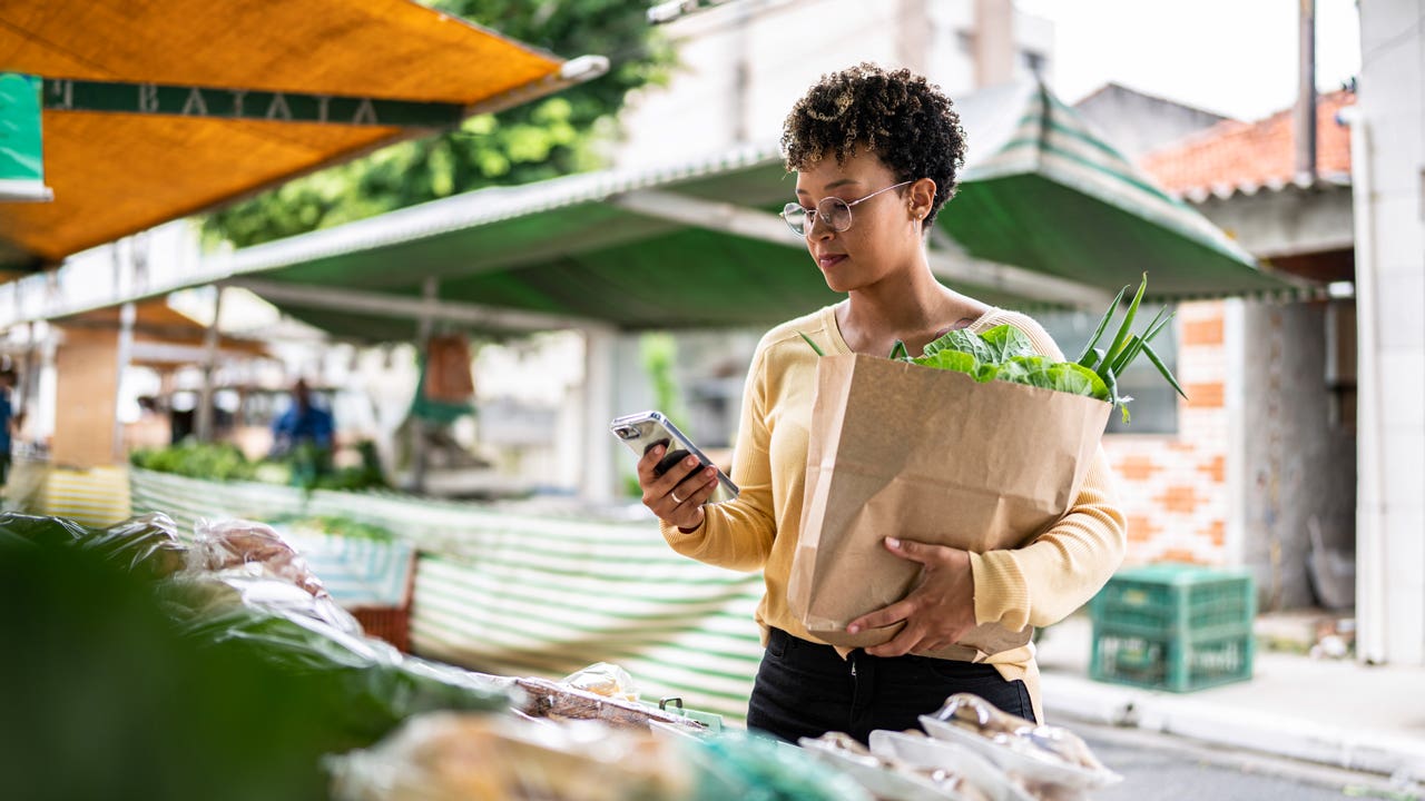 young lady on her phone at a street stand