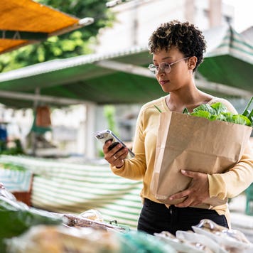 young lady on her phone at a street stand