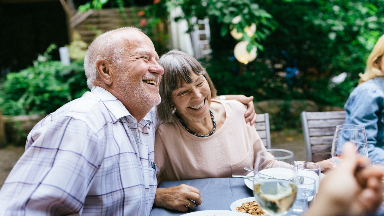 A smiling older couple dining outside