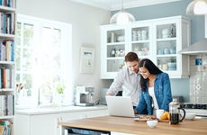 A couple looks at their laptop computer in their kitchen
