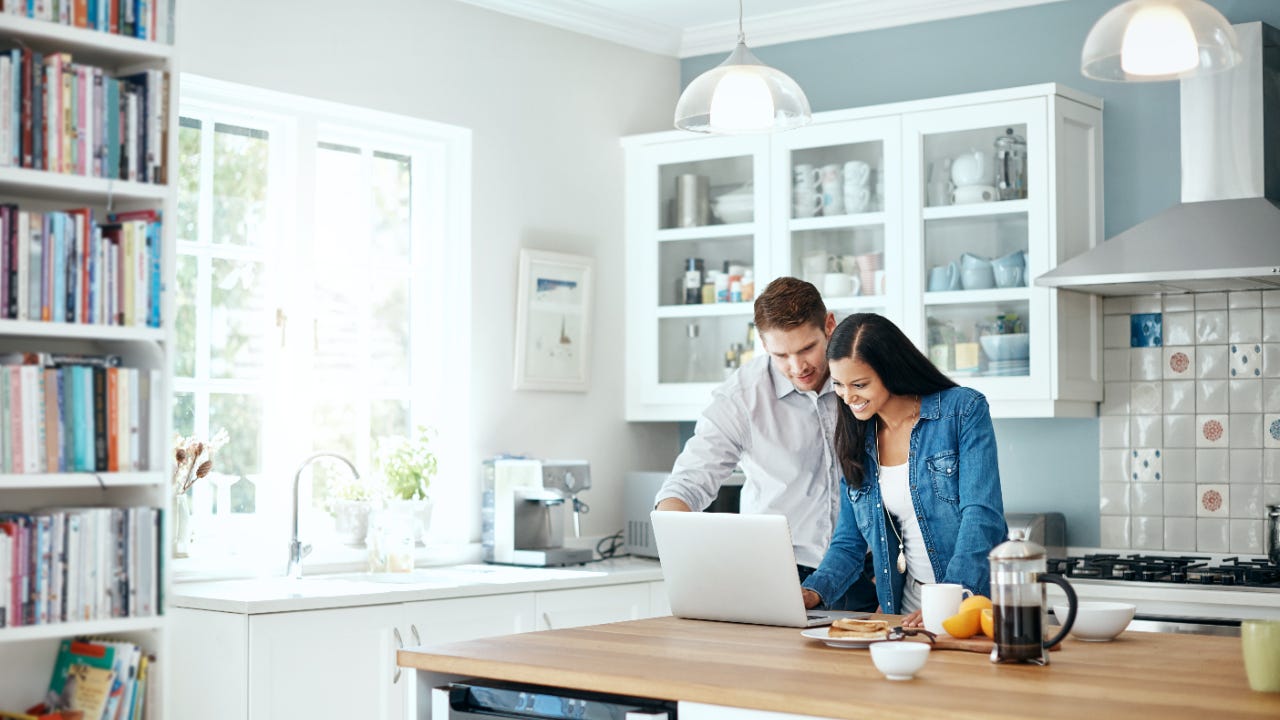 A couple looks at their laptop computer in their kitchen