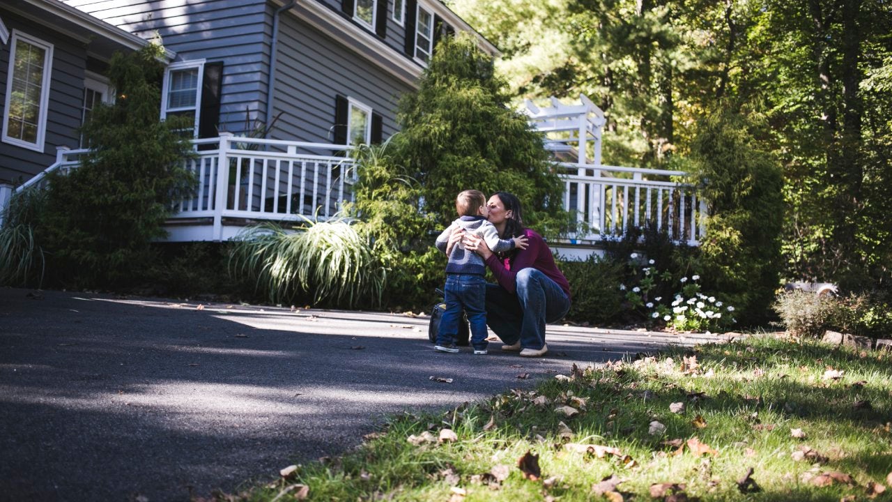 Mother kissing toddler son in driveway