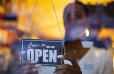 Woman turning the "open" sign on a business