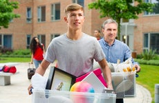 Man and son carry boxes to dorm room